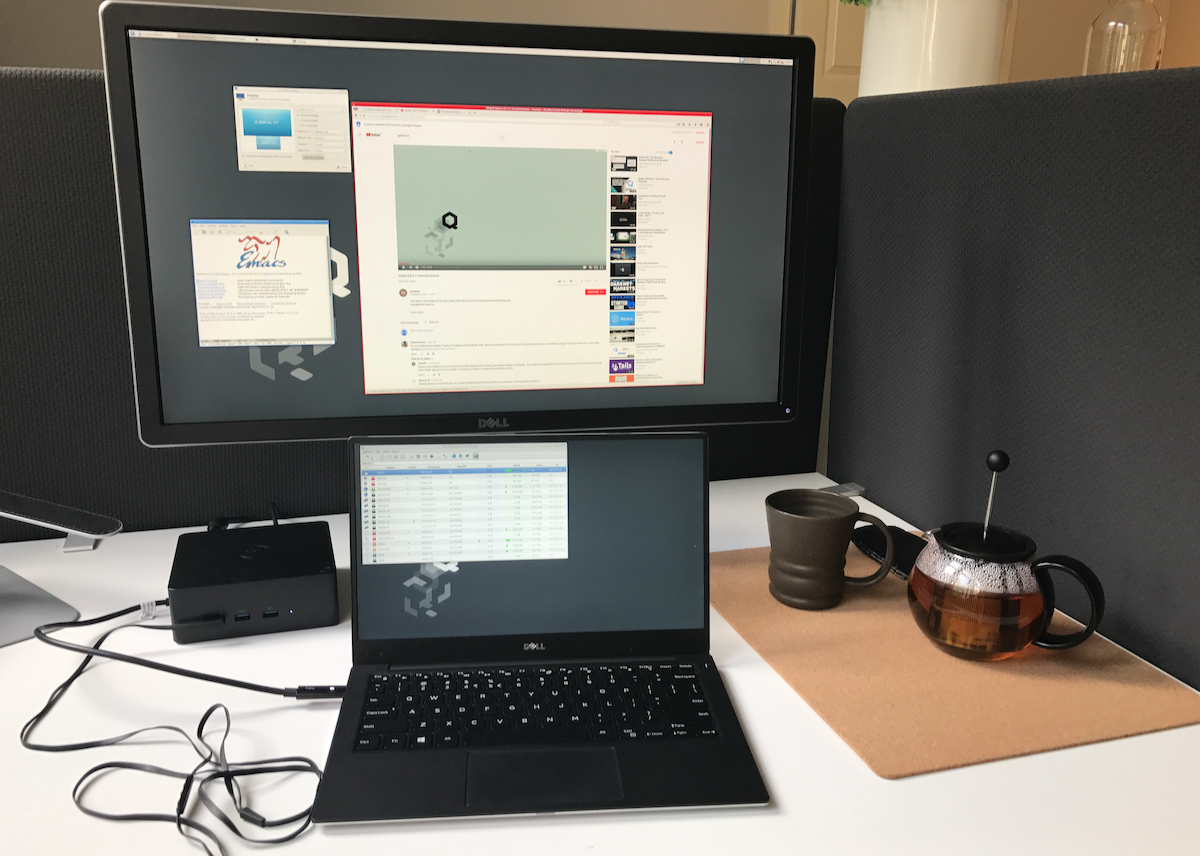 A workstation desk with a laptop running Qubes OS and a teapot on the side
